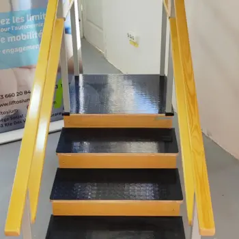 Vue de face de l'escalier de rééducation kinésithérapie Liftosium montrant les marches antidérapantes noires et les mains courantes parallèles en bois.